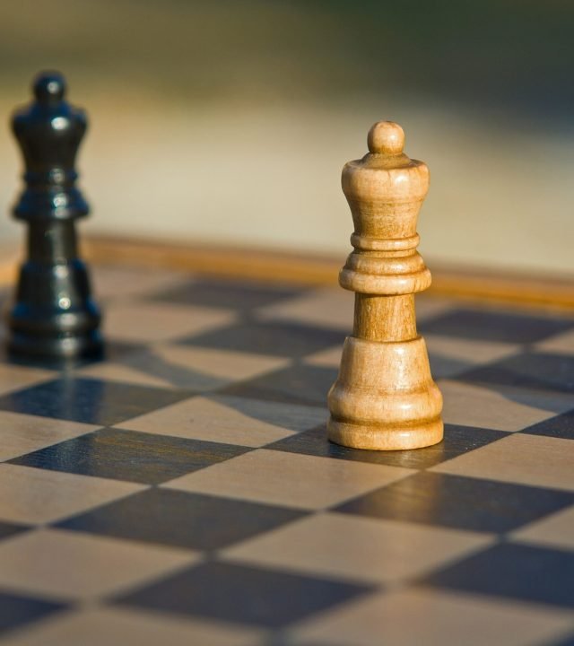 Detailed view of chess pieces on a classic wooden chessboard outdoors.