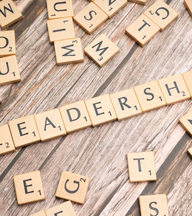 Wooden letter tiles spelling 'LEADERSHIP' on a wooden surface, symbolizing leadership qualities and skills.