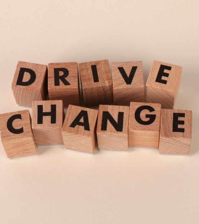 Wooden blocks spelling 'Drive Change' on a neutral background, symbolizing motivation and growth.