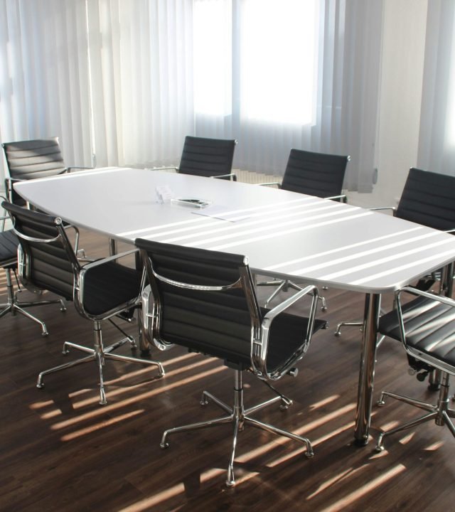 Modern office meeting room with designer chairs, table, and large windows.