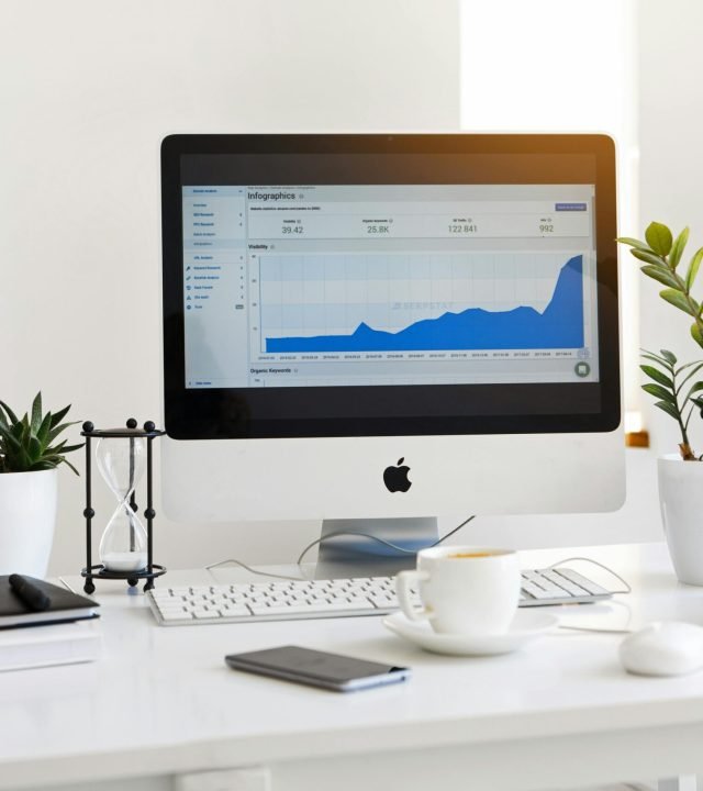 A clean, contemporary workspace featuring a desktop with analytics on the screen and plants for a fresh look.
