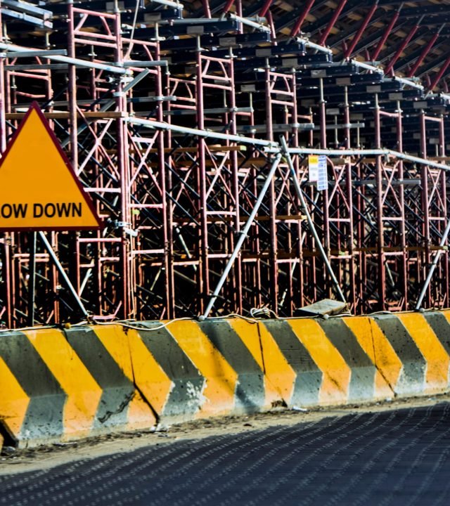 Construction site with a 'Slow Down' sign amid scaffolding in Kuwait.